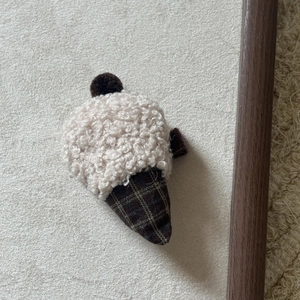 Close-up of handmade ice cream hair clip with cream fleece ball and brown cone fabric
