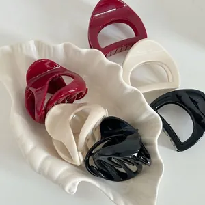 Elegant pumpkin hair clips in red, cream, and black on a white leaf ceramic tray