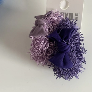 Vue détaillée des chouchous violets en peluche avec texture bouclée et nœud en tissu doux