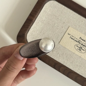 Close-up of a vintage minimalist hair clip featuring a large white pearl on a dark matte base