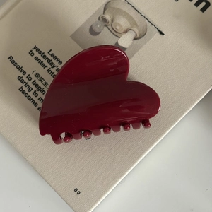 Détail d'une pince à cheveux en forme de cœur rouge bordeaux brillant sur un livre