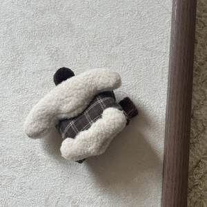 Close-up of handmade cream plush cake hair clip with plaid fabric and brown pompom