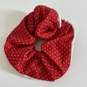 Détail d'un chouchou rouge à pois avec bords blancs volantés et texture de tissu plissé