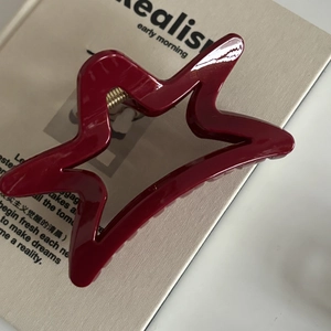 Détail macro de la pince à cheveux étoile rouge bordeaux avec finition brillante et ressort