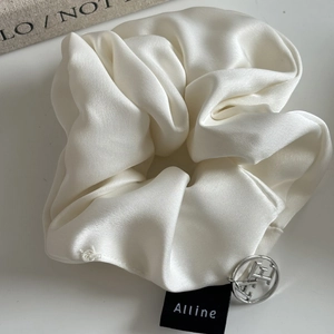 Elegant white silk satin scrunchie with silver logo pendant and premium brand label