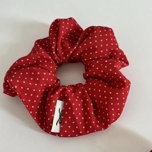 Détail d'un chouchou rouge à pois blancs avec étiquette de marque et texture plissée