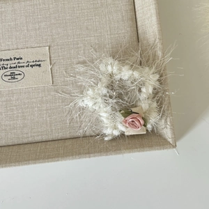 Détail d'un chouchou en tricot blanc pelucheux orné d'une délicate rose en tissu rose