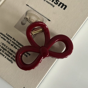 Détail d'une pince à cheveux nœud bordeaux avec finition brillante et ressort doré