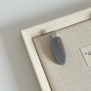 Dettaglio del fermaglio in acetato grigio con scritta dorata Barrette la France