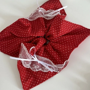 Détail d'un chouchou rouge à pois avec bordure en dentelle blanche et petits nœuds