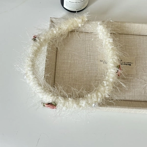 Détail d'un chouchou en maille blanche avec fleur rose et perles de nacre élégantes