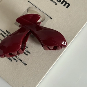 Détail de la pince à cheveux rouge foncé brillante avec un design incurvé élégant