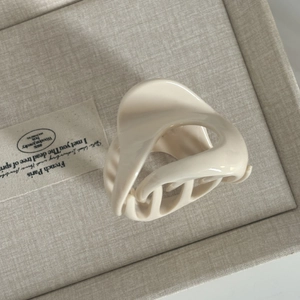Detail of off-white resin hair claw clip with a minimalist fluid geometric design