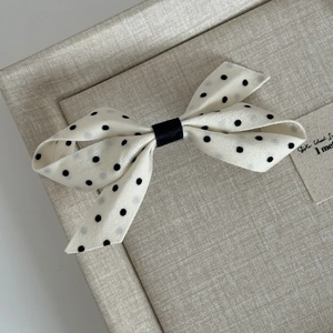Elegant white satin hair claw clip with black polka dots in a classic bow design