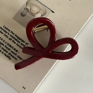 Gros plan sur la pince à cheveux rouge bordeaux avec fini brillant et ressort doré