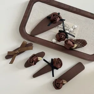 Detail of vintage brown hair clips with fabric roses, satin bows and pearls in a wooden tray