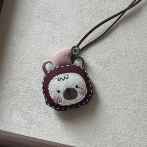 Close-up of handmade fabric bear necklace with pink nightcap and brown leather cord
