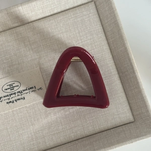 Detail view of burgundy triangle claw clip with premium glossy finish and gold spring
