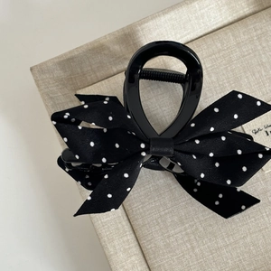Close-up of vintage black shark hair clip with polka dot bow and metal spring mechanism