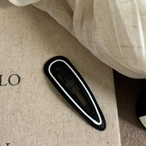 Close-up of minimalist black and white striped teardrop BB hair clip on linen background