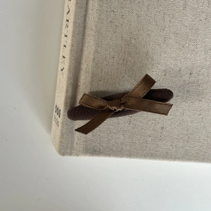 Close-up of a brown velvet bow hair clip on a vintage cloth book cover for styling