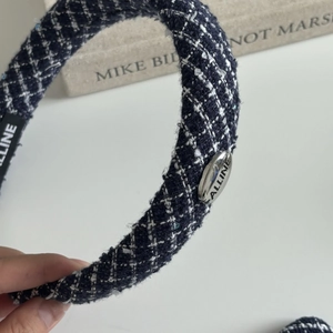 Detailed close-up of navy tweed headband with metallic oval ornament and woven texture