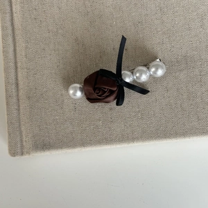 Detail of French style hair clip with brown silk rose, white pearls and black ribbon bow