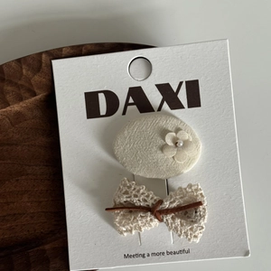 Détail d'un ensemble de barrettes à fleurs et dentelle sur carte de présentation