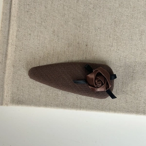 Detail of coffee brown fabric hair clip with a handmade satin rose and silk ribbon leaves