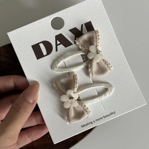 Gros plan de deux barrettes à nœuds crème avec pétales de fleurs et fausses perles