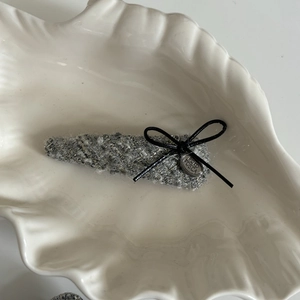 Pinza per capelli in tweed grigio con fiocco nero e ciondolo argento su vassoio