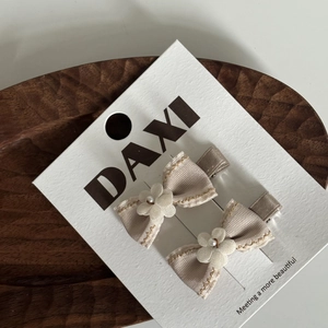 Vue détaillée de barrettes à nœud beige avec perles sur un plateau en bois