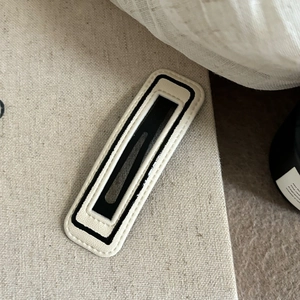 Minimalist black and white striped rectangular BB hair clip with leather texture on linen