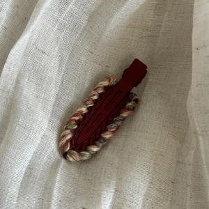 Detail of sweet burgundy yarn-wrapped no-crease hair clip with retro woven texture