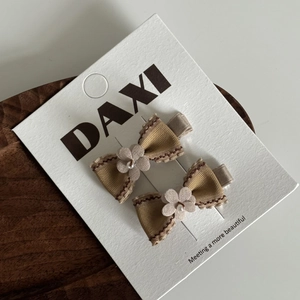 Détail de barrettes à nœuds kaki avec fleurs et perles sur une carte de présentation