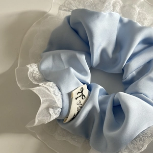 Elastico per capelli in raso azzurro con bordo in pizzo bianco ed etichetta tessuta