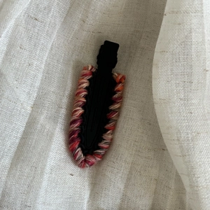 Detailed view of handmade knitted hair clip with colorful wool on black metal duckbill clip
