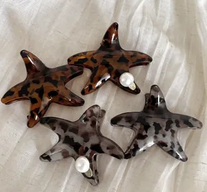 Dettaglio di fermagli a stella marina in acrilico tartarugato con decorazioni di perle
