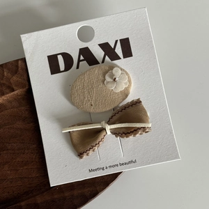 Gros plan sur barrette en tissu beige avec fleur 3D et nœud en ruban marron élégant