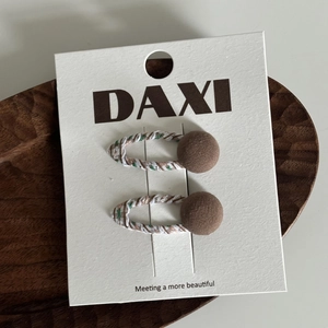 Détail de barrettes à rayures vertes avec bouton marron sur carte de présentation