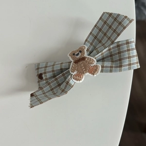 Detail of blue and brown plaid bow hair clip featuring a cute embroidered bear patch