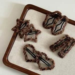 Plush leopard print hair clips set in star and heart shapes on a beige fabric tray