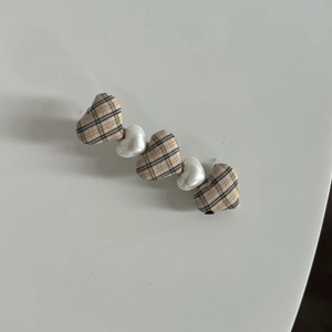 Detail of sweet checkered fabric hearts and white pearls on a stylish hair clip