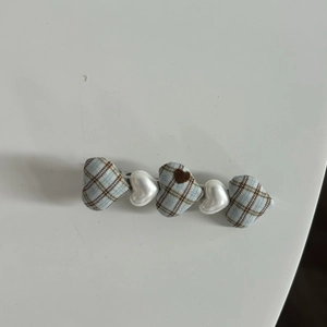 Detail of sweet heart-shaped hair clips featuring blue plaid fabric and white pearls