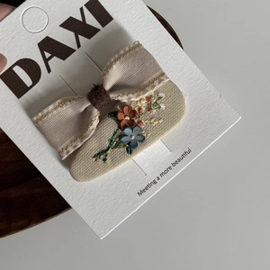 Gros plan sur la barrette à nœud beige et la broderie florale faite main sur tissu souple
