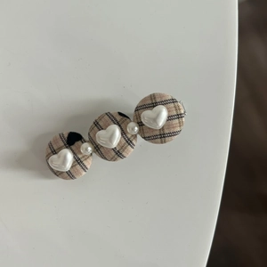 Close-up of plaid fabric hair clip with white heart buttons and pearl beads details