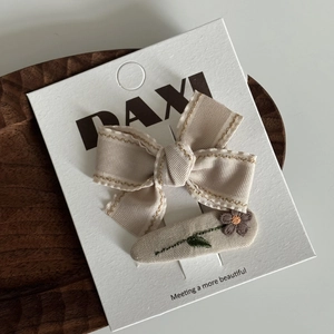 Détail de la pince à cheveux beige et de l'épingle fleur marguerite brodée sur carte