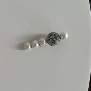 Detail view of plaid fabric button hair clip with pearls and small silver bow