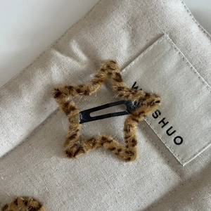 Close-up of leopard print plush star-shaped hair clip on minimalist canvas texture