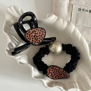 Set elegante di elastico leopardato e molletta nera su un vassoio decorativo a conchiglia
